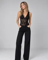 Top de encaje negro con escote en V pronunciado y tirantes anchos, confeccionado con un diseño translúcido.
