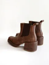 Bota tipo chelsea de cuero color chocolate con acabado texturizado, plataforma y taco cuadrado. Presenta paneles elásticos laterales en color negro.