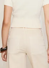 Jeans Catherin de tiro alto, diseño culotte y pernera recta con bajo deshilachado, en color beige. Cuentan con trabillas para cinturón, bolsillos de parche traseros y cierre frontal de cremallera y botón.