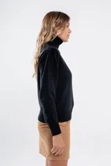Polera de tejido de punto color negro, con cuello tortuga alto y puños y ruedo acanalados.