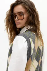 Chaleco de punto color gris con estampado de rombos (argyle) en beige y verde lima. Tiene escote en V, botones frontales y terminaciones de rib.