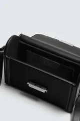 Bandolera rígida tipo caja, color negro, con solapa frontal y cierre metálico horizontal. Incluye asa de hombro ajustable.