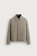 Sobrecamisa color gris topo de corte boxy fit, confeccionada en tejido compacto. Cuenta con cuello clásico, manga larga con puño abotonado, bolsillos frontales tipo parche y cierre frontal de botonadura oculta.