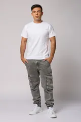 Pantalón jean gris claro, estilo jogger, con bolsillos cargo laterales y puños elásticos en los tobillos.