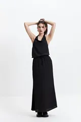 Musculosa negra con detalle drapeado, cuello bote y espalda descubierta.