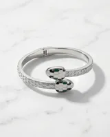 Esclava rígida de acero con diseño de serpiente, decorada con esmalte blanco y detalles en verde en la cabeza.