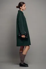 Trench midi ZW Collection verde oscuro con cuello solapa, manga larga, bolsillos laterales en costura y cierre frontal con botones. Cuenta con forro interior a contraste y detalle de solapa corta en el pecho.