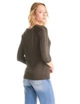 Buzo de tejido fino en color blanco, con cuello redondo y mangas raglán tres cuartos. Presenta una línea de tachas decorativas a lo largo de las mangas.