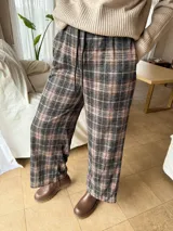 Pantalón wide leg de corte relajado con estampado de cuadros en tonos grisáceos y líneas terracota. Presenta cintura elastizada con cordón de ajuste y bolsillos laterales.