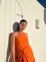 Vestido largo naranja de crepé con escote en pico y falda tipo pareo regulable.