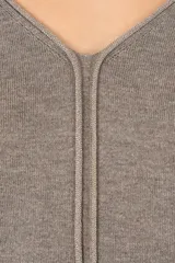 Suéter de punto color gris con cuello en V, manga tres cuartos y detalle de costura central vertical. Presenta un diseño de silueta holgada y terminaciones acanaladas en puños y ruedo.