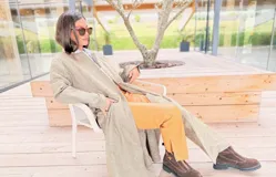 Tapado largo de paño liviano con diseño de cuadros en tonos marrones. Presenta solapas clásicas, bolsillos laterales con detalles en cuero y tajos profundos en los costados.