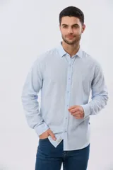 Camisa de manga larga confeccionada en mezcla de lino y algodón, con sutiles rayas celestes, cuello camisero clásico y cierre frontal de botones.