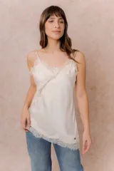 Musculosa de satén color crema con breteles finos regulables, escote en V y detalles de encaje en el escote, en diagonal sobre el delantero y en el ruedo.