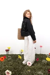 Pantalón amplio de lino blanco, tiro medio/bajo, con bolsillos delanteros y trasero, y botón metálico grabado. Presenta bordados laterales y traseros.