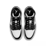 Championes Nike Air Jordan 1 Mid con diseño de caña media, combinando paneles de cuero blanco y negro. Presenta el icónico logo Swoosh en los laterales y el emblema Air Jordan Wings en el cuello.