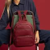 Mochila de tamaño mediano confeccionada en símil cuero color beige, con doble bolsillo frontal con cierre metálico, asa de mano superior y correas regulables de cinta tejida.