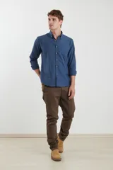 Camisa de vestir blanca de manga larga, con cuello abotonado, bolsillo frontal y botones en tono madera.