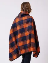 Capa de tejido cuadrille con diseño de cuadros en tonos marrón, beige y naranja. Presenta un cierre frontal con botón tipo trenca y bordes con ribete negro.