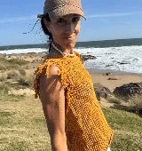 Musculosa tejida en punto calado, color violeta, con diseño sin mangas y detalle de flecos en los hombros.