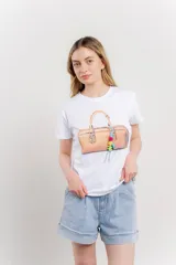 Remera blanca de algodón con estampado de un bolso con llavero colorido.
