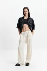 Camisa de manga corta confeccionada en cuero sintético negro, con cuello clásico, cierre frontal con botones y bolsillos delanteros con solapa.