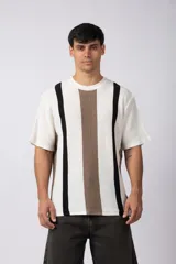 Remera de tejido de punto con textura piqué, de manga corta y corte relajado. Presenta un diseño de rayas verticales en tonos blanco, negro y marrón.