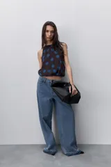 Jean negro de tiro alto y pierna wide leg, confeccionado en denim de caída firme con diseño de cinco bolsillos, pasacintos, cierre frontal con botón y ruedo desflecado.