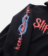 Buzo con capucha de corte relajado, color negro, con estampado frontal y en la manga con el logo de la banda Slipknot en tonos rojos y azules.