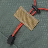 Mochila urbana y de senderismo marca Caterpillar, color verde con detalles en naranja y marrón. Presenta un diseño ligero en tejido ripstop hexagonal, con cordón elástico frontal para almacenamiento, bolsillos laterales de malla, compartimento principal con bolsillo interior y logo reflectante.