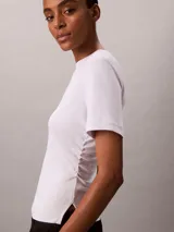 Remera Calvin Klein de manga corta y cuello redondo, color blanco, confeccionada en algodón pima. Presenta costuras verticales en el frente y un sutil logo script de la marca bordado en el pecho.