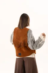 Chaleco oversize confeccionado en cuero descarne, con diseño de terminación en picos, detalle de tachas metálicas en los bordes frontales y flecos en la espalda.