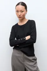 Remera de manga larga en color blanco, con cuello redondo y detalle de botones en los puños.