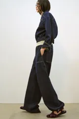 Sandalia plana tipo cangrejera confeccionada en material con efecto terciopelo. Presenta diseño de tiras entrelazadas, punta redonda y cierre mediante hebilla metálica lateral.