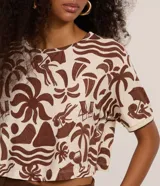 Blusa cropped de cuello redondo y manga corta, confeccionada en viscosa con elastano, con estampa de iconos playeros en tonos marrón sobre base beige y ribetes en las mangas.