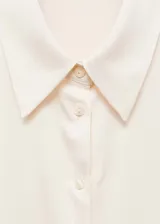 Camisa de corte recto y tejido satinado con acabado fluido. Presenta cuello clásico, cierre frontal de botones y mangas largas con puños abotonados.