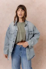 Camisa de jean de calce relajado y lavado claro con efecto vintage. Presenta cuello clásico, cierre frontal con broches metálicos, mangas largas con puños y dos bolsillos con tapa en el frente.