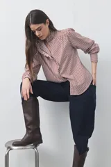 Camisa de manga larga a rayas verticales en tonos blanco y bordó, con cuello alto y detalle de volados frontales. Presenta puños con volados y un corte fluido.