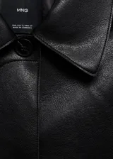 Chaqueta corta de efecto piel en color negro, con cuello de solapa, cierre frontal de botones y dos bolsillos de parche con solapa en la parte delantera. Presenta un diseño recto y forro interior.