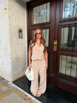 Chaleco de corte sastrero en tela tusor color beige con sutiles rayas verticales, escote en V y cierre frontal con botones al tono.