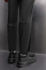 Pantalón negro de entrenamiento slim fit confeccionado en tejido técnico ligero y elástico con estructura. Cuenta con cintura elástica ajustable con cordón, bolsillos frontales y trasero con cierre de cremallera, y bajo ajustable con cremallera en laterales.