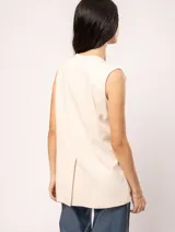 Chaleco color crema de lino con corte sastrero, largo a la cadera, forro interno, botones delanteros, silueta levemente entallada y tajo cruzado en la espalda.