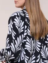 Camperita de lino liviana, marca Dash, con estampado botánico de hojas en tonos azules, verdes y tostados sobre base blanca. Presenta cierre frontal con botones, cuello clásico y bolsillos aplicados en el pecho.
