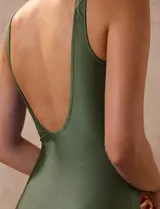 Malla enteriza de color verde militar, con diseño cruzado en V, detalle de drapeado lateral en la cintura, breteles anchos fijos y espalda pronunciada en U.