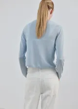Cardigan de punto fino color celeste, con cuello redondo, manga larga y cierre delantero con botones.