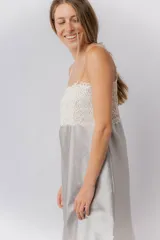 Camisón de satén elastizado color gris claro, con escote recto y detalle de puntilla elastizada en el busto y espalda. Tiene breteles finos regulables y un largo por encima de la rodilla.