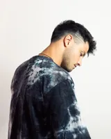 Remera negra con efecto tie-dye y logo pequeño en el centro del pecho.