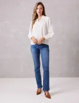 Blusa de gasa con plisado soleil, cuello a la base fruncido con escote en V regulable mediante lazos, y mangas largas abullonadas con puños sastreros.