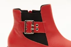 Botín de cuero negro con elásticos laterales, aplique metálico con ojales y cierre lateral con cremallera. Taco cuadrado desfasado de 3 cm.