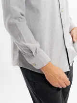 Camisa de corte regular confeccionada en tejido oxford, color azul claro. Presenta cuello con botones, cierre frontal abotonado, mangas largas con puños y un bolsillo frontal en el pecho.
